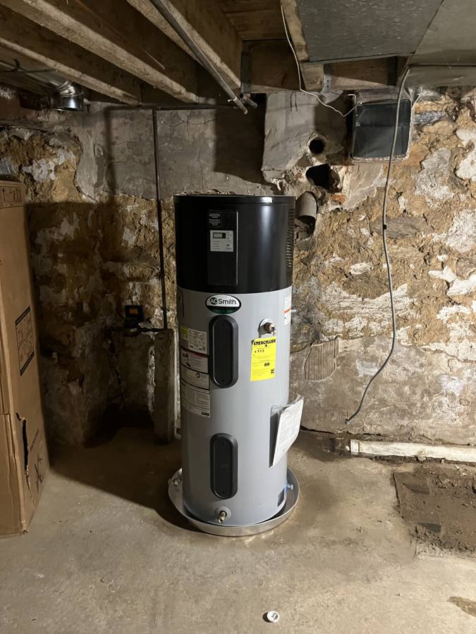 AO Smith heat pump water heater on a drain pan in a stone cellar