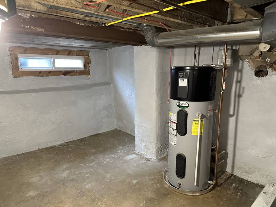 AO Smith heat pump water heater on a drain pan in a painted basement